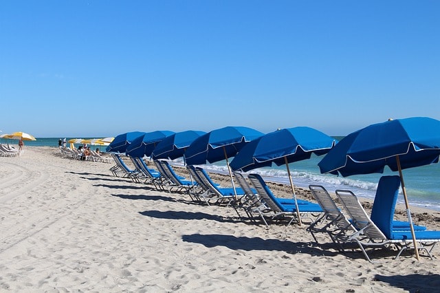 Plage de miami avec transats et parasols bleus.