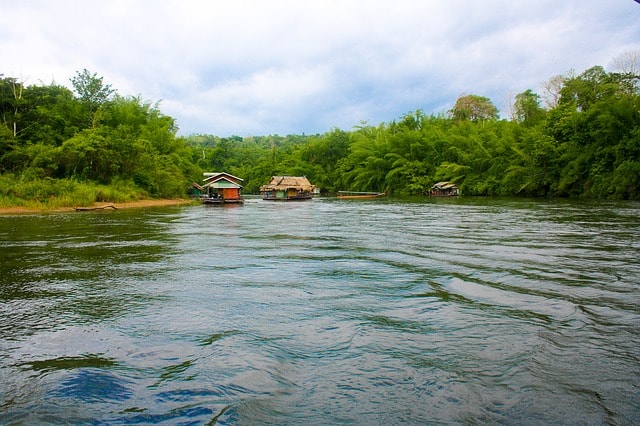 La rivière Kwai bordé d'arbres et quelques maisons flottantes.